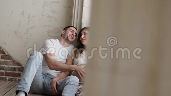幸福的夫妻正坐在地板上丈夫抚摸着怀孕的妻子的肚子视频的预览图