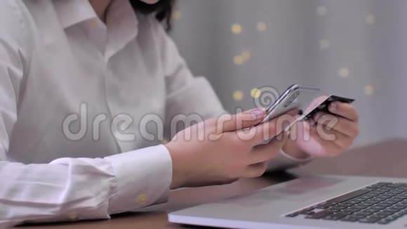 这位黑发女人坐在家里用智能手机上的信用卡通过互联网进行在线支付视频的预览图