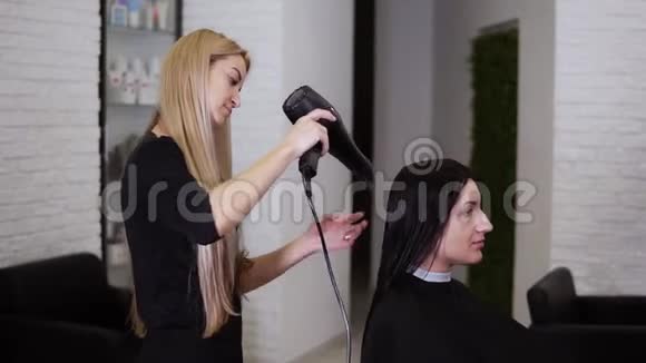 在理发店新理发之前一位白种人黑发的年轻女性被美容师理发弄干了头发视频的预览图