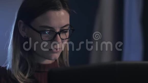 工作的女人漂亮的女人晚上在电脑上工作微笑着打印文本戴着眼镜看监视器视频的预览图