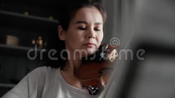 可爱的年轻女子在家里拉小提琴慢动作特写视频的预览图