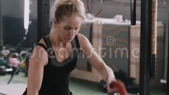 年轻漂亮的金发女郎用战绳锻炼到极限休息一下在大型健身房微笑视频的预览图