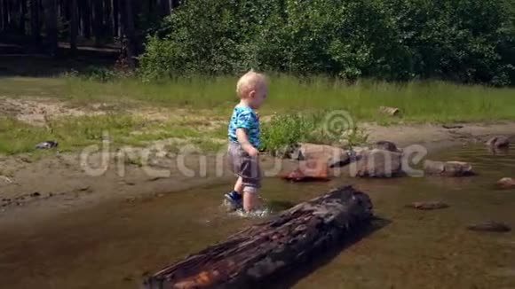 一个阳光明媚的夏日小男孩踩在森林湖的水面上视频的预览图