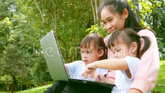 快乐的亚洲家庭在夏天在花园里看笔记本电脑视频的预览图