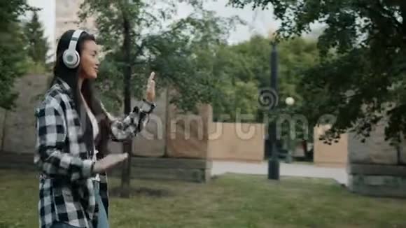 亚洲女士戴耳机在城市公园户外慢动作视频的预览图