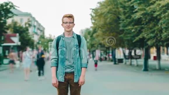 在城市的步行街上站着一个有魅力的红发男子视频的预览图