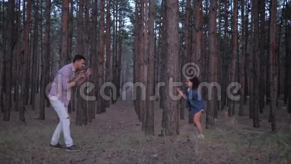 一家人在森林里玩得很开心年轻的爸爸在假日里和小女儿在一排排松树之间玩耍视频的预览图