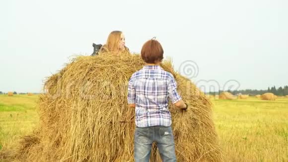 男孩站在地上女孩躺在干草堆上视频的预览图