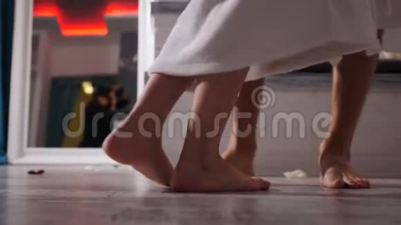 男女腿的特写镜头慢慢地跳舞穿浴袍的年轻人在水疗中心休息赤脚踩在地板上视频的预览图