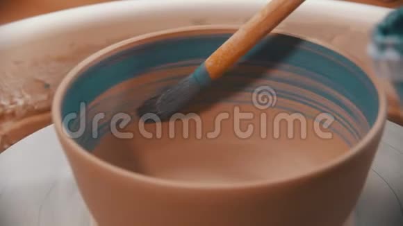陶工正在用蓝色的画笔在陶轮上画一个陶碗视频的预览图