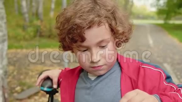 可爱的孩子站在公园里骑自行车视频的预览图