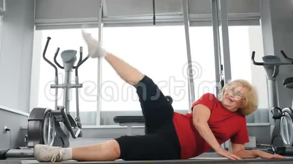 晚年健康的生活方式决心微笑的高白种人妇女在健身室做运动锻炼视频的预览图