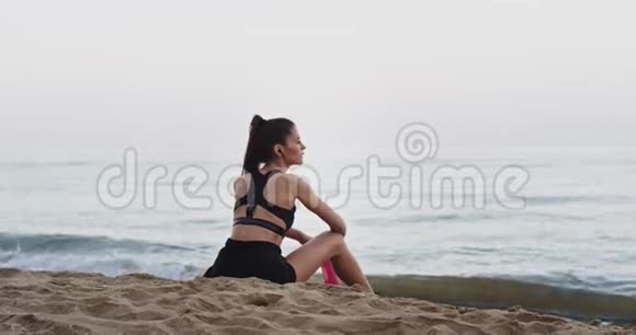 健康的生活方式概念运动的女士在海边锻炼后在海边喝干渴的水和视频的预览图