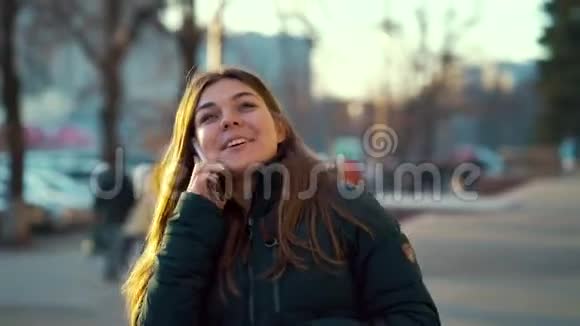 在日落时分在街上使用智能手机的快乐女孩视频的预览图