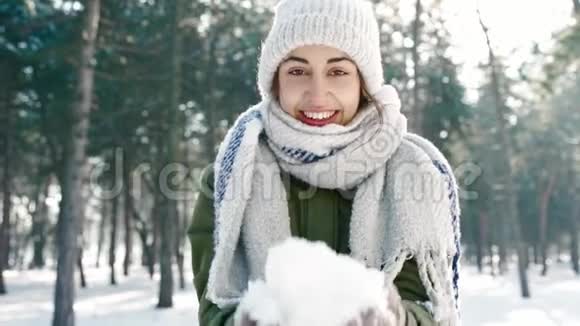一幅滑稽的微笑女人的特写肖像她戴着一顶宽大的帽子戴着一条长长的温暖围巾手里拿着雪手里拿着雪视频的预览图