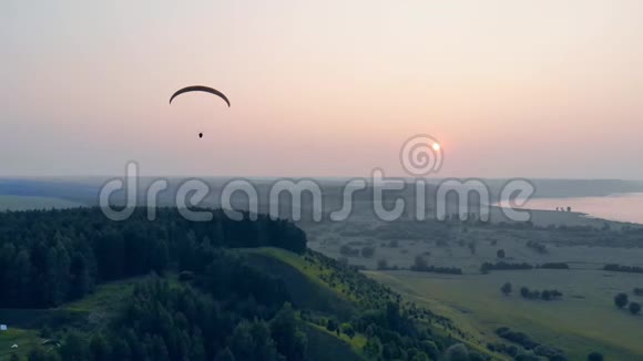 一个运动员带着滑翔机在日落背景下飞行滑翔伞动作极限运动理念视频的预览图