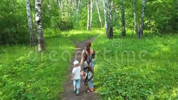 一位年轻的母亲带着一个孩子在公园里散步妈妈紧紧地握住宝宝手视频的预览图