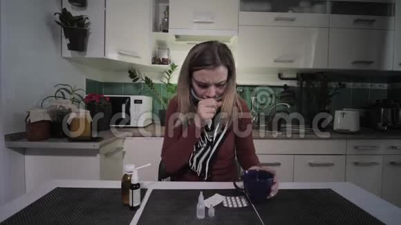 疾病的季节感冒的女性咳嗽和病毒冻结喝一杯饮料喉咙痛坐在厨房视频的预览图