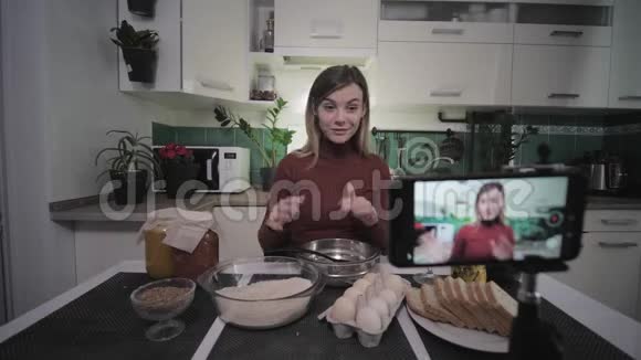 美丽的家庭主妇博客写食谱食品智能手机上的用户在社交网络直播期间视频的预览图