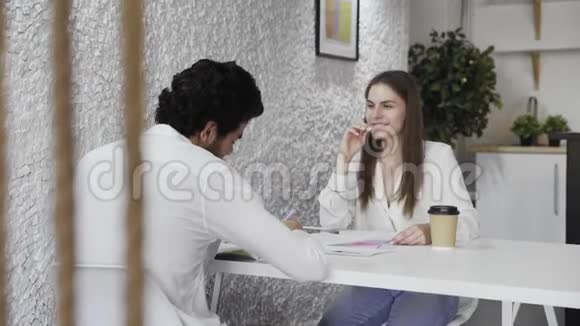 年轻的商人在阁楼办公室聊天一个迷人的女人和一个男人说话笑视频的预览图