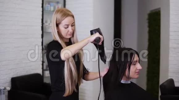 在理发店新理发之前一位白种人黑发的年轻女性被美容师理发弄干了头发视频的预览图