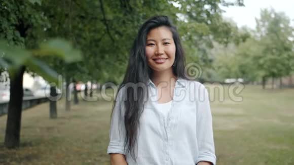 美丽的亚洲女人在城市公园外独自微笑表现出良好的手势视频的预览图