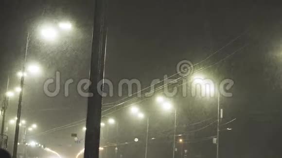 在漆黑的冬夜里街灯发光圣诞夜降雪中的城市灯笼落雪的路灯视频的预览图