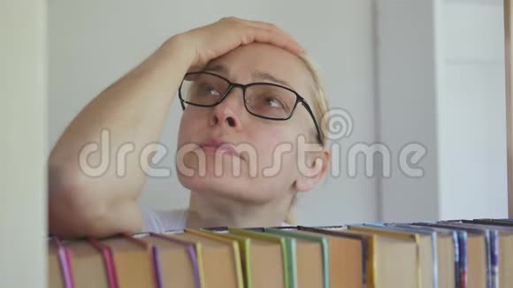 一位妇女站在书架旁双手捂着头闭上眼睛视频的预览图