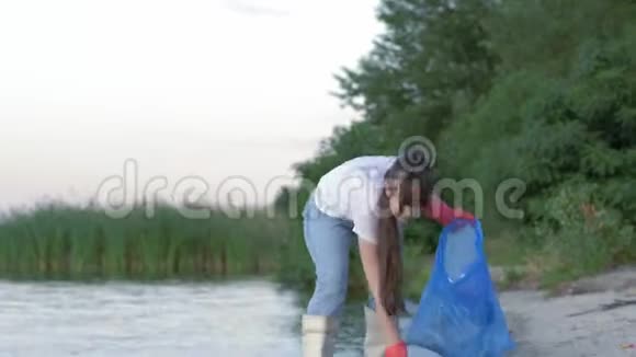 环境问题年轻的活动家女孩穿着橡胶靴清理海滨的塑料垃圾和收集视频的预览图