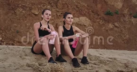 运动型的女士们享受早上锻炼后的时光坐在海边视频的预览图