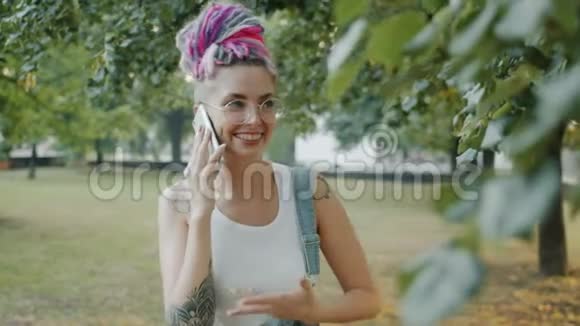 带着牙套的快乐女孩在城市公园的手机上聊天笑视频的预览图