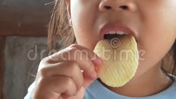 快乐的亚洲小女孩在花园里吃薯片视频的预览图