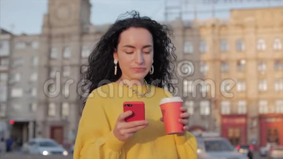 女青年穆斯林在市中心散步使用智能手机和饮用咖啡网上概念交流视频的预览图
