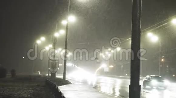 在漆黑的冬夜里街灯发光圣诞夜降雪中的城市灯笼落雪的路灯视频的预览图