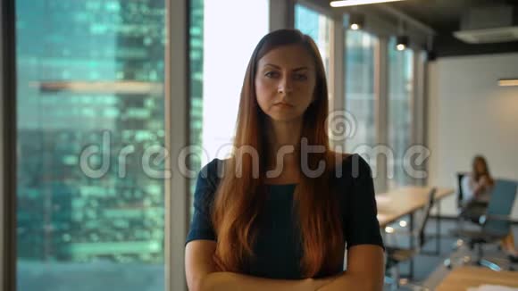 年轻成功的红发女商人站在办公室大厅看镜头的画像视频的预览图