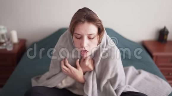 一个喉咙痛发烧的不健康的年轻女人在卧室里用毯子盖上被子供暖问题视频的预览图