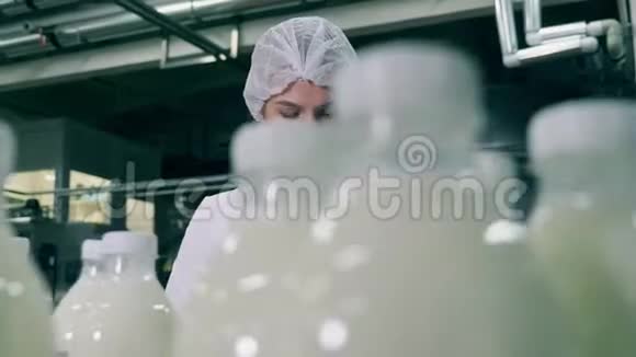 工厂生产线的质量控制女工厂工人技师在一条线上用牛奶检查瓶子视频的预览图