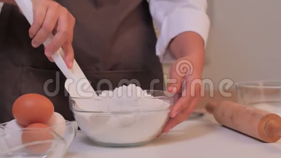视频幻灯片特写女人的手正在用白色的铲子把面粉混合在一个透明的杯子里视频的预览图