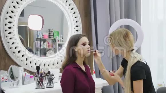 专业化妆师致力于年轻女孩在美容院创造自然的外观视频的预览图