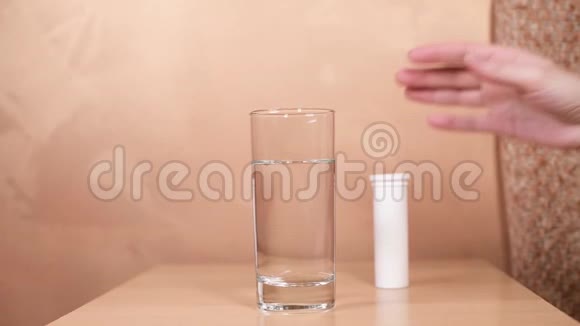 女孩的手随便地把两个放进一杯水里放在桌子上视频的预览图
