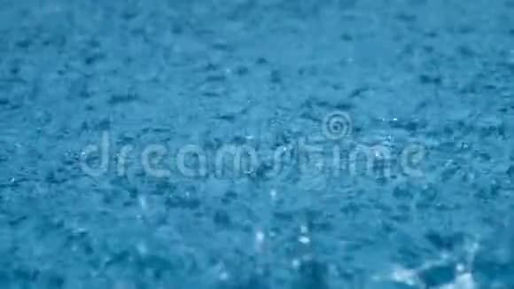 特写雨雨滴缓慢地落在一个大水坑里雨季视频的预览图