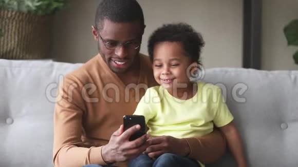 非洲父亲和儿子一起玩智能手机视频的预览图