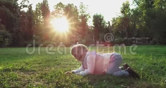 夕阳西下一个大可爱的小男孩微笑着站在绿色公园中央的草地前穿着一套休闲服视频的预览图