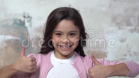 小女孩独自一人被隔离在彩绘的墙上竖起大拇指表示快乐视频的预览图