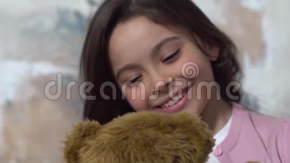 小女孩独自一人被隔离在墙上看着玩具熊快乐视频的预览图