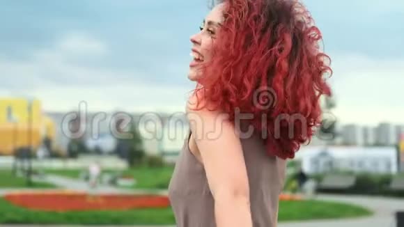 美丽的滑稽女孩红色卷发在天空背景下旋转缓慢视频的预览图