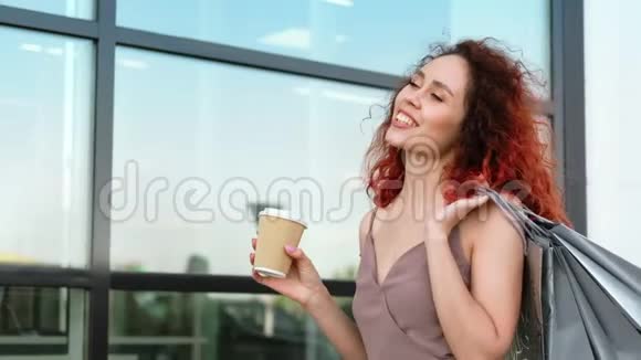 微笑的买家女人挥舞着头发走在玻璃商场的窗前视频的预览图