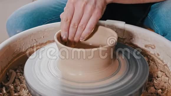 手工陶工雕刻一个更宽的壶形侧面靠近顶部视频的预览图