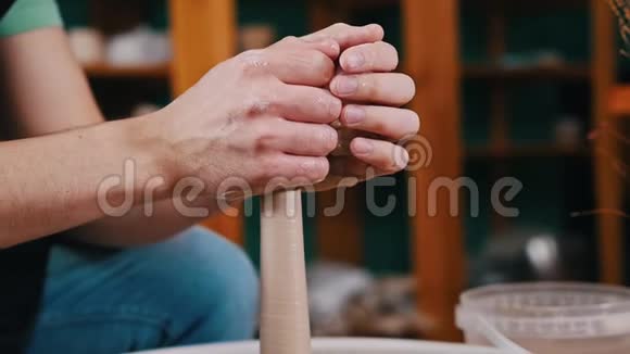 一个人的手在陶工的车轮上旋转形成一块形状更长的粘土视频的预览图