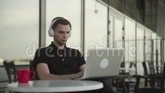 清晨一个迷人的男人在咖啡馆里通过平板电脑在线交谈喝着咖啡视频的预览图